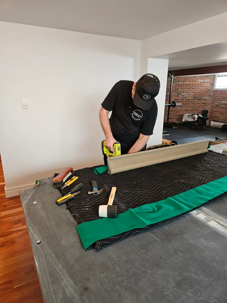 Technicien travaillant sur le tissu vert d’une bande de billard