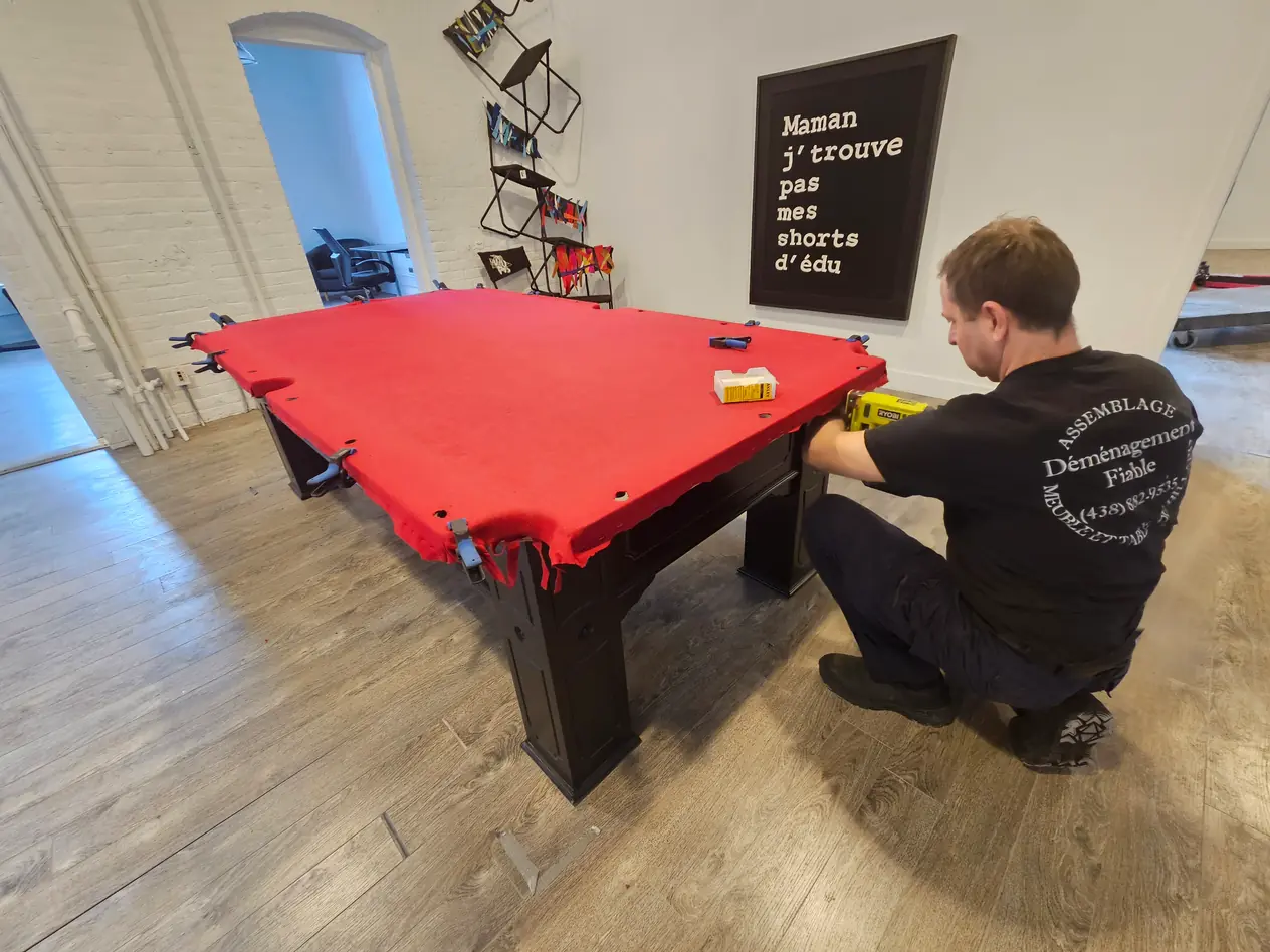 Technicien au travail sur une table de billard à tapis rouge